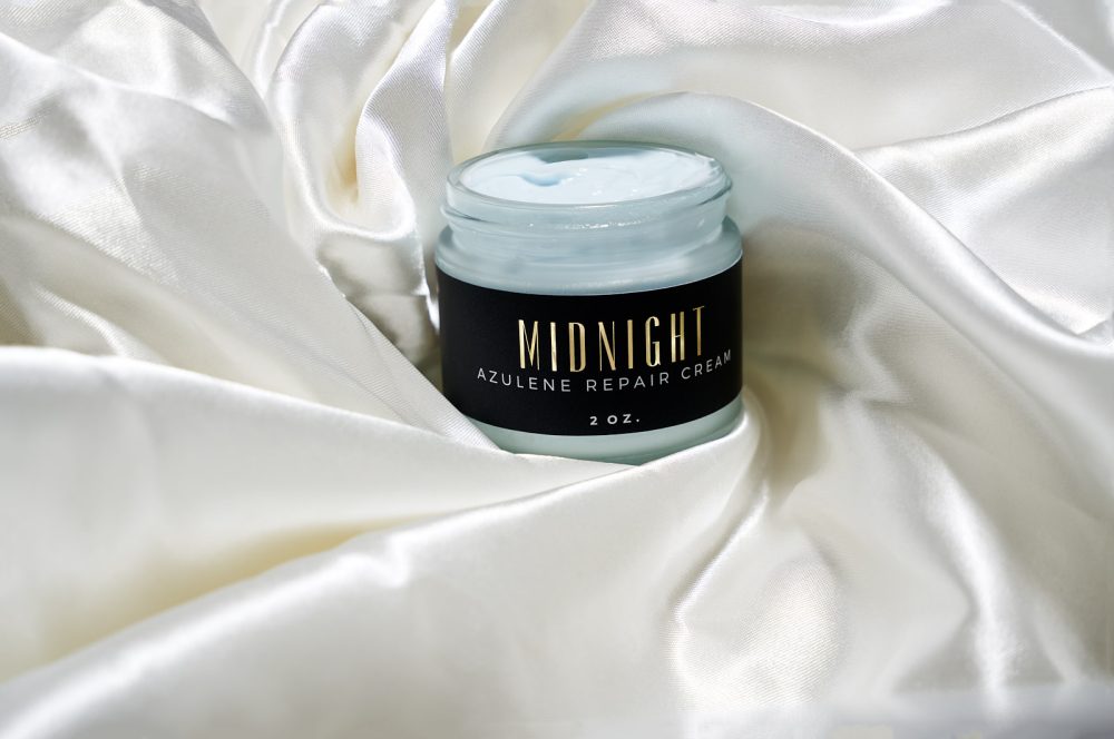 Skincare brand marketing shoot featuring Azulene Repair Cream elegantly placed on luxurious satin sheets, highlighting the product’s premium quality and sophisticated appeal in a refined setting.